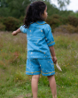 A child pointing to something in the distance, wearing the Little Green Radicals Organic Cotton Dusk Button Through Pyjama Short Set. Made from GOTS organic Cotton, these beautiful light blue pyjama shorts and top have delicate stars and moon designs