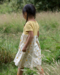 Girl walking in a grass field wearing the little green radicals short sleeve sunshine and rainbows easy peasy dress