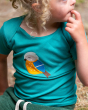 A child is sitting outside whilst wearing the Little Green Radicals Little Bird Applique Short Sleeve T-Shirt. Made from GOTS Organic Cotton, a beautiful green t-shirt with a sleepy bird applique which has a yellow belly, a blue with, a brown tail and bea