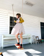Girl stood swinging on the grand oak swing on a white wooden porch