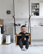 Toddler sat in the Lillagunga eco-friendly wooden toddler swing hanging in a white kitchen