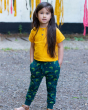 A child stood outside wearing a yellow t-shirt and the Little Green Radicals Organic Cotton Little Lizard Comfy Joggers. Made with GOTS Organic Cotton, these joggers are a lovely deep forest green with a playful chameleon lizard print, a drawstring cord i