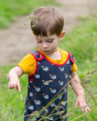 Close up of child wearing the Little Green Radicals fairtrade whale song dungarees in some long grass