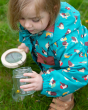A child exploring mini beasts in a glass jar, wearing the Little Green Radicals Garden Birds Recycled Waterproof Windbreaker Jacket, made from 100% Recycled Polyester, this beautiful jacket is windproof and waterproof. The coat is a beautiful teal green, 