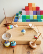 Mader wooden spinning top toys on a Mader spinning plate next to a Grimms Large Stepped Pyramid
