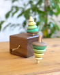 Close up of a Mader spinning top spinning next to a Mader wooden music box