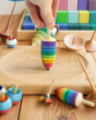Close up of hand holding the Mader rainbow thunderbolt spinning top toy on a Mader spinning plate