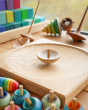 Mader wooden UFO spinning top on a Mader spinning plate surrounded by wooden spinning tops and a Grimms Large Stepped Pyramid