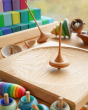 Mader wooden Ibis spinning top on a Mader spinning plate surrounded by wooden spinning tops and a Grimms Large Stepped Pyramid