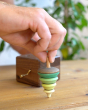Close up of a hand holding the spinning top from the Mader wooden music box on a wooden table