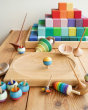 Mader rainbow thunderbolt spinning top toy next to a Mader spinning plate and other wooden spinning tops 