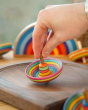 Close up of a hand holding a mader plastic free wooden sombrero spinning top on a mader spinning plate