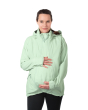 A person wearing the Mamalila Outdoor Explorer Babywearing Jacket - Mint, with their hands on their stomach over the top of the coat