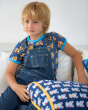 Young boy sat on a white sofa wearing the Maxomorra eco-friendly navy denim dungarees