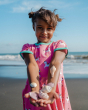A child holding shells in their hands whilst wearing the Maxomorra Unicorn Organic Cotton Children's Short Sleeve Circle Dress