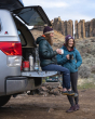 Two adults happily sat and stood next to their car, ready for camping and drinking from the Klean Kanteen 12oz Insulated Mugs. The background is of a rocky formation on top of a small hill