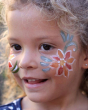 Young girl with a Natural Earth face paint flower on her cheek