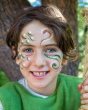 Close up of child holding a rope, with Natural Earth eco-friendly face paint drawn into green and red swirls on their cheeks
