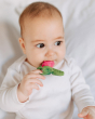 Close up of a baby chewing on the oli and carol ramonita radish teether on a white bed