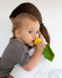 Close up of a woman holding a baby with an Oli & Carol natural rubber lemon teething toy in it's mouth