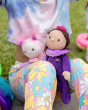 A child holding Freya Fondant and Clara cupcake on their lap, sat on a grassy field