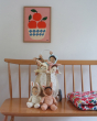 An Olli Ella Luggy Basket, stood on a long bench chair carrying the Olli Ella Dinky Dinkum Doll Fluffles collection
