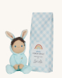 Olli Ella Dinky Dinkum Doll Fluffles - Basil Bunny, wearing a fluffy light all in one with fluffy bunny ears, and blue packaging on a  cream background