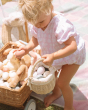 A child happily playing an egg hunt, using the Olli Ella Rattan Berry Basket with Lining – Pansy Floral. 