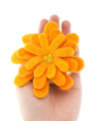 Close up of a Papoose plastic-free felt flower toy in the palm of a hand on a white background