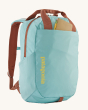 A closer view of the Patagonia Atom Tote Backpack 20L - Skiff Blue, showing a notebook and pencil in the outer front pocket, on a cream background