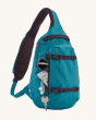 Patagonia Atom Sling 8L - Patchwork bag in Vessel Blue with items in the front pocket and a key clipped to the side of the zipper