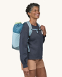 An adult with the Patagonia Ultralight Black Hole Tote Pack on their shoulder, showing the chest clip and shoulder straps