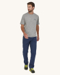 An adult wearing the Patagonia Men's Capilene Cool Daily Graphic Shirt in grey, wearing long navy blue trousers and yellow trainers