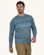 An adult wearing a Patagonia Men's Long-Sleeved Capilene Cool Daily Graphic Shirt in blue with stripes showing the fit of the top from the front