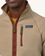 An adult wearing a Patagonia Men's Retro Pile Jacket - Dark Natural / Utility Blue, showing the Patagonia logo on the chest, and zippers