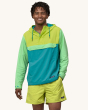 A person wearing Patagonia Men's Baggies Beach Shorts - Phosphorus Green, and a lightweight yellow, blue and light green pull over jacket, showing the fit of the shorts from the front