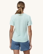 An adult wearing the Patagonia Women's Capilene Cool Trail Graphic Shirt - Forge Mark Crest / Wispy Green, and light grey/blue shorts. This photo shows the fit of the top from the back