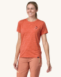 An adult showing the swift on the front of the Patagonia Women's Capilene Cool Daily Graphic Shirt - Granite Swift / Pimento Red X-Dye, on a cream background