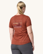 An adult wearing the Patagonia Women's Capilene Cool Daily Graphic Shirt. This photo shows the fit on the back of the t-shirt, on a cream background