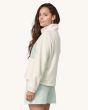 An adult wearing the Patagonia Women's Microdini 1/2 Zip Fleece Pullover - Birch White with a light blue pocket The photo also shows the fit of the fleece from the side