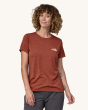 An adult wearing the Patagonia Women's Capilene Cool Daily Graphic Shirt. This photo shows the fit of the t-shirt from the front, on a cream background
