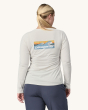 An adult wearing the Patagonia Women's Long-Sleeved Capilene Cool Daily Graphic Shirt in white showing the fit of the top from the back