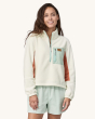 An adult wearing the Patagonia Women's Microdini 1/2 Zip Fleece Pullover - Birch White with a light blue pocket and zips, a brown Patagonia logo on the pocket, and brown fleece material on the inside of the arms. The photo also shows the fit of the fleece