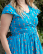 Close up of woman wearing the Piccalilly short sleeve organic cotton wrap dress in the blue and red parrot print