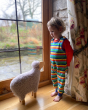 Boy stood in front of a window next to a sheep ornament wearing the Piccalily childrens organic cotton rainbow stripe dungarees