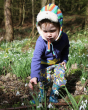 Young child reaching forward to touch a flower wearing the PIccalily organic cotton rainbow print clothing