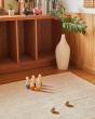 Plantoys solid wooden bowling game set on a beige carpet in front of some wooden shelves