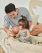 Young girl and man sat on a blanket playing with the PlanToys wooden baby car toy