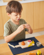 Close up of a young boy holding pieces of play food from the PlanToys charcuterie board toy set