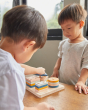 Close up of two young boys playing with the PlanToys geometric orchard shape sorting toy on a wooden table